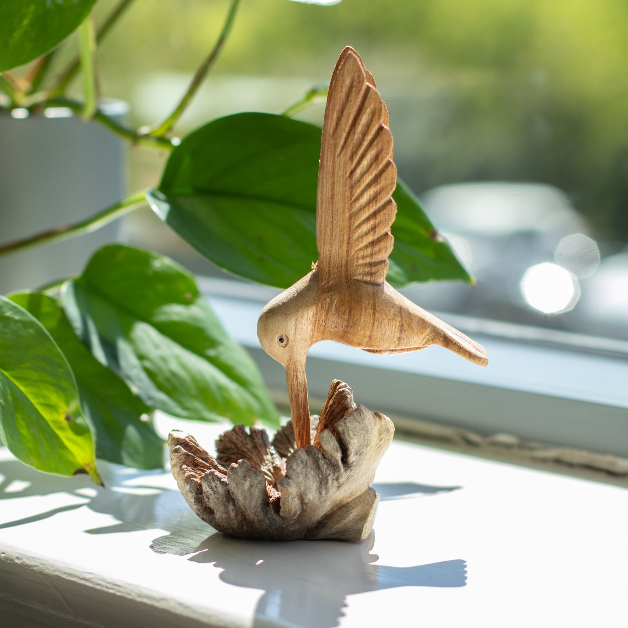 Scultura artigianale di colibrì che beve nettare da una gemma legnosa