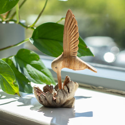 Scultura artigianale di colibrì che beve nettare da una gemma legnosa