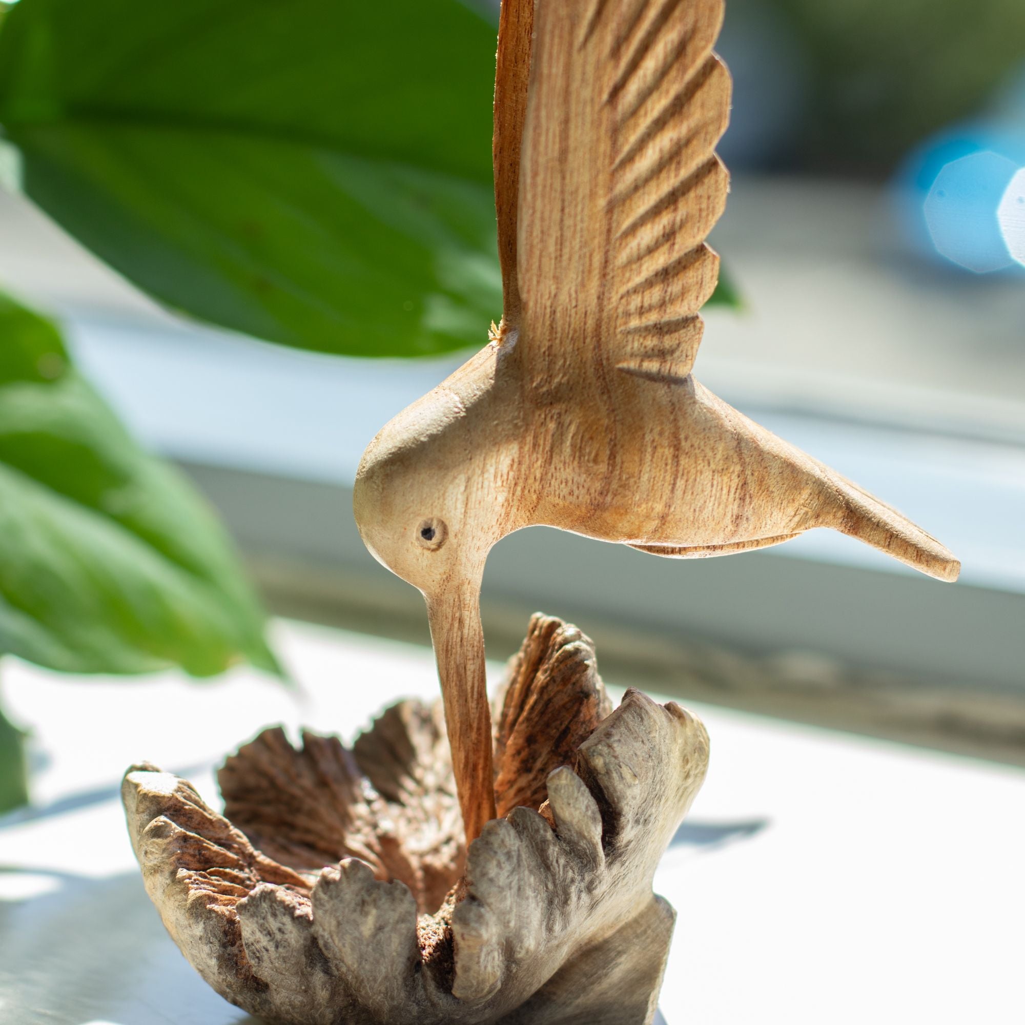 Scultura artigianale di colibrì che beve nettare da una gemma legnosa