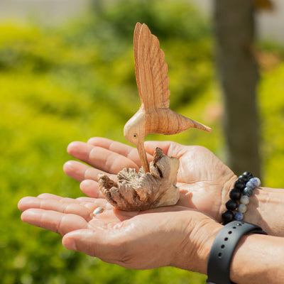 Scultura artigianale di colibrì che beve nettare da una gemma legnosa